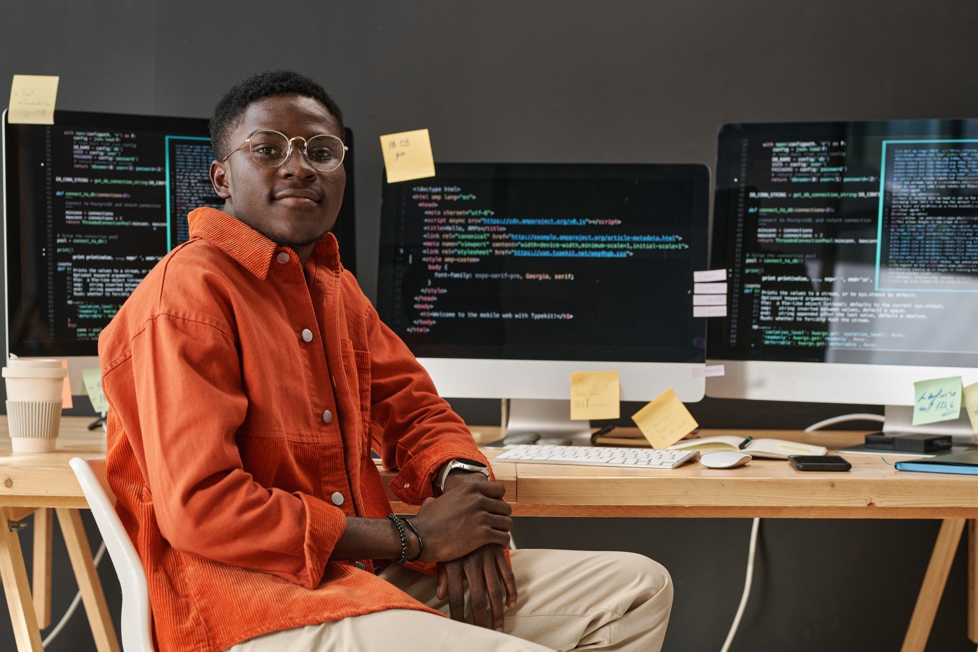 Young IT support manager looking at camera while sitting by workplace
